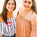 2 smiling women wearing brown knit tops